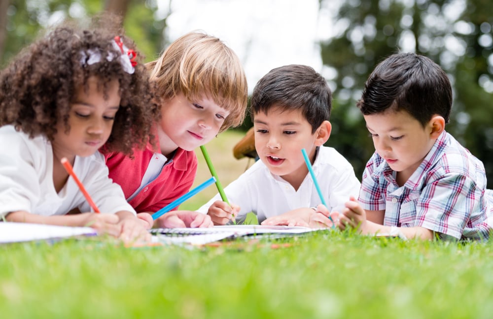 Group of school kids coloring outdoors looking happy Group of school kids coloring outdoors looking happy
